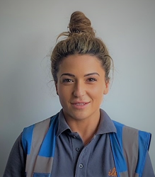 Person wearing a polo shirt and safety vest, smiling at the camera.