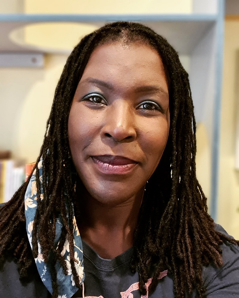 Person smiling in front of bookshelves.