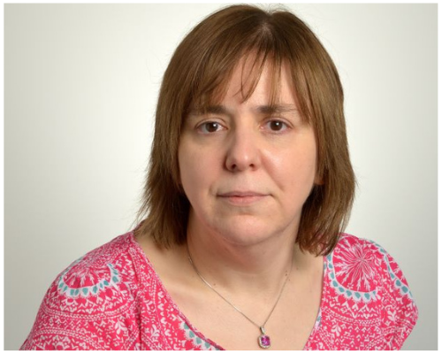 Person wearing a pink patterned shirt with straight hair.