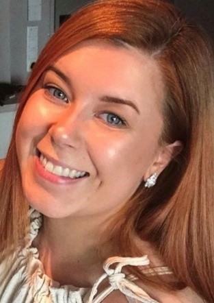 Person smiling with long hair and a white top.