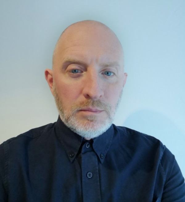 Person with a serious expression, wearing a dark shirt.