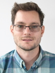 Person wearing glasses and a plaid shirt against a plain background.