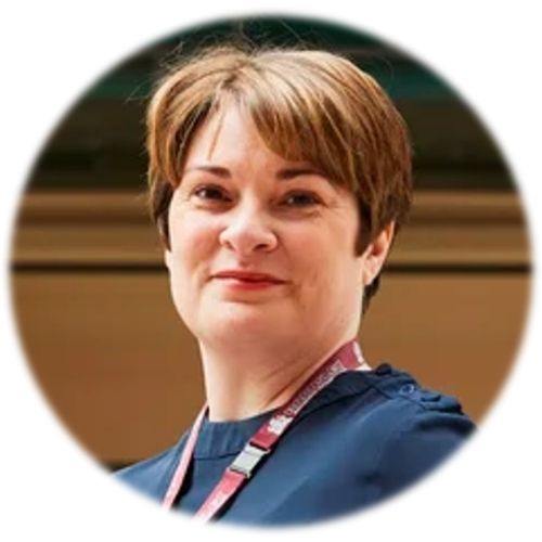 Person smiling with short hair, wearing a badge.