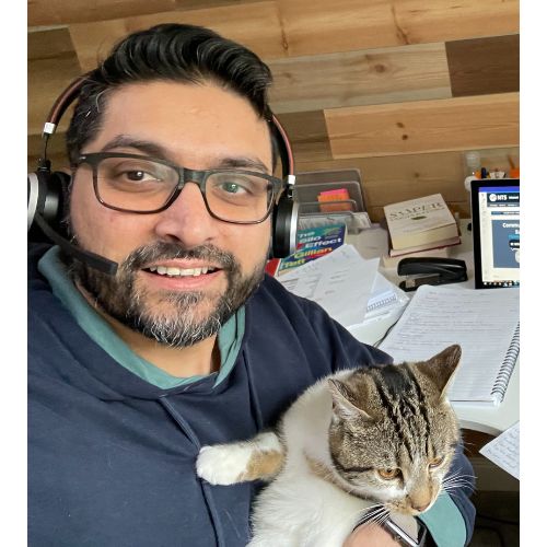 Person working remotely with a headset, holding a cat in a home office setup.