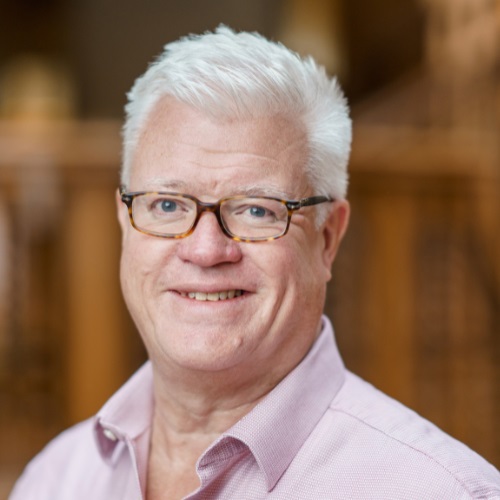 Person with glasses smiling in a light-colored shirt.