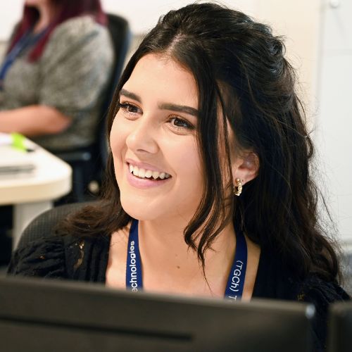 Person smiling at a desk in an office setting.
