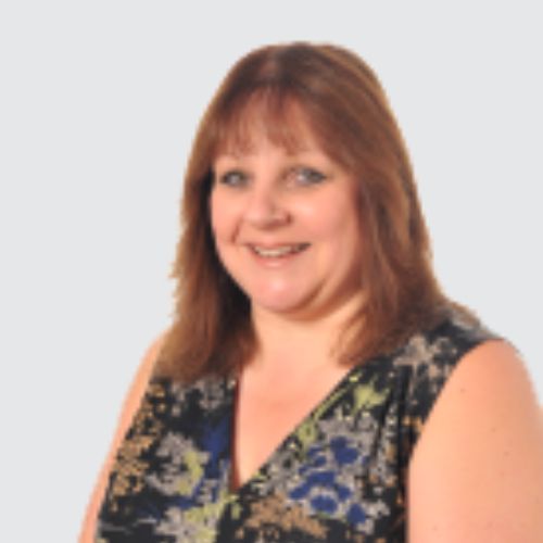 Smiling person with shoulder-length hair wearing a floral top against a light background.