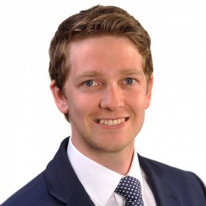 Person smiling in a suit and tie, facing the camera.