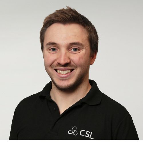 Person smiling in a black polo shirt with CSL logo.