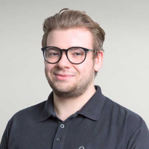 Person wearing glasses and a dark polo shirt, smiling.