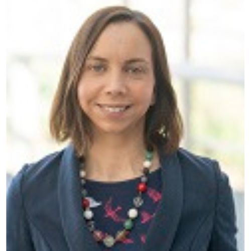 Person smiling wearing a colorful necklace and blue blazer