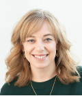 Smiling person with shoulder-length hair wearing a green top.
