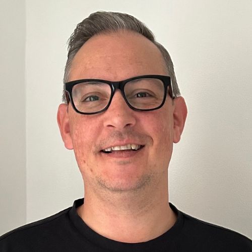 Person wearing glasses smiling at the camera.