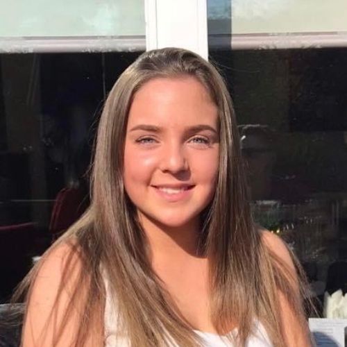 Person smiling in sunlight with long hair.