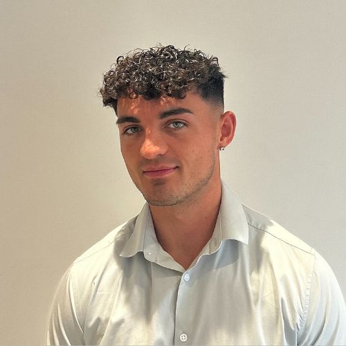 Person with curly hair in a light shirt against a plain background.