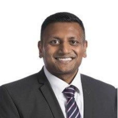 Person in a suit smiling against a white background.