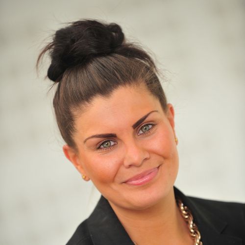 Person smiling warmly with hair styled in a bun.