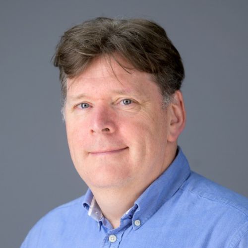 Person with a friendly expression wearing a light blue shirt.