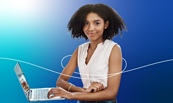 A youg woman, smiling and working on a laptop