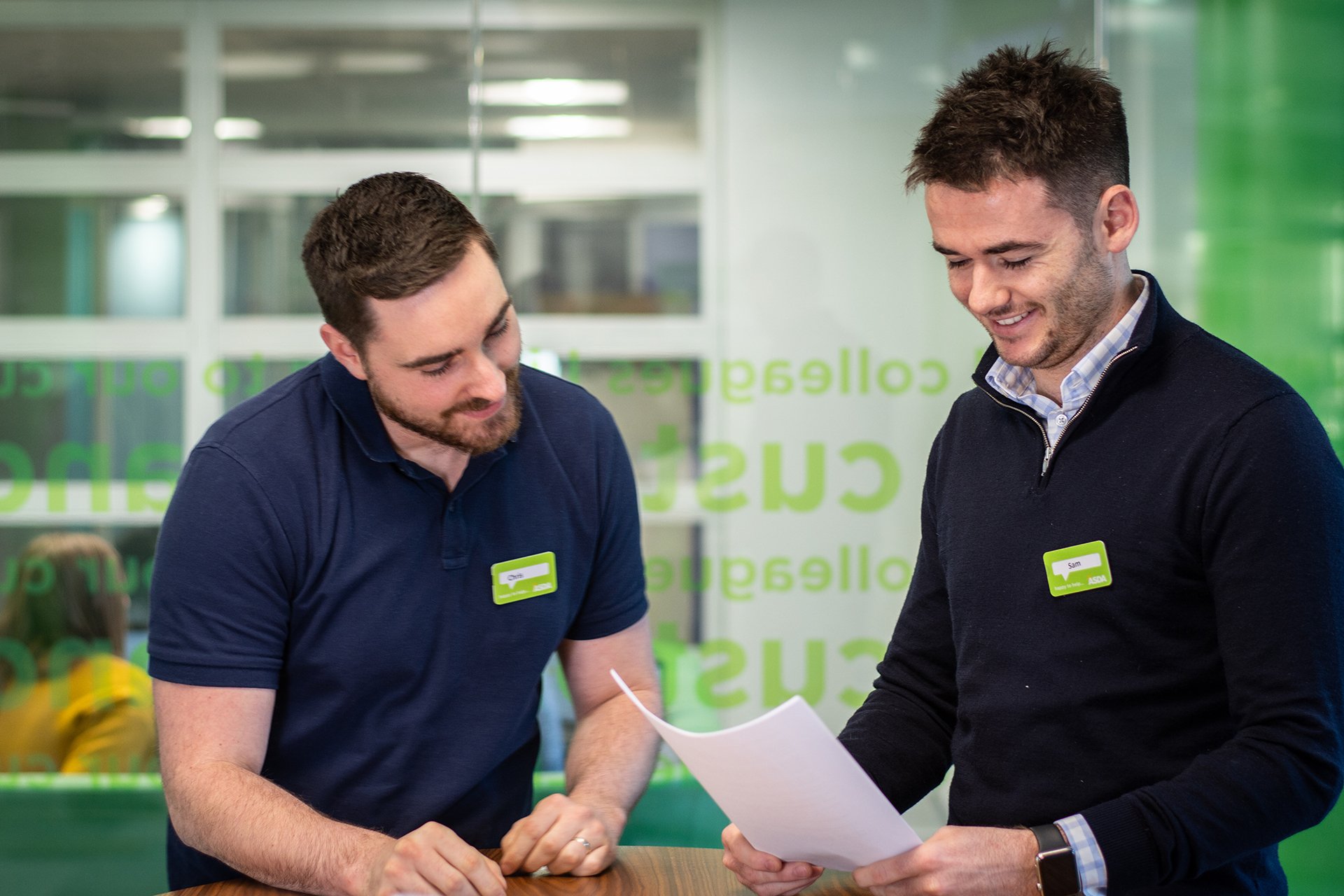 Two male Asda employees collaborating on a document