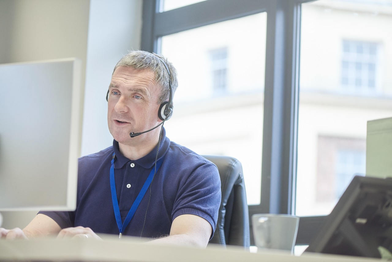 middle-aged man at an office desktop wearing a headset