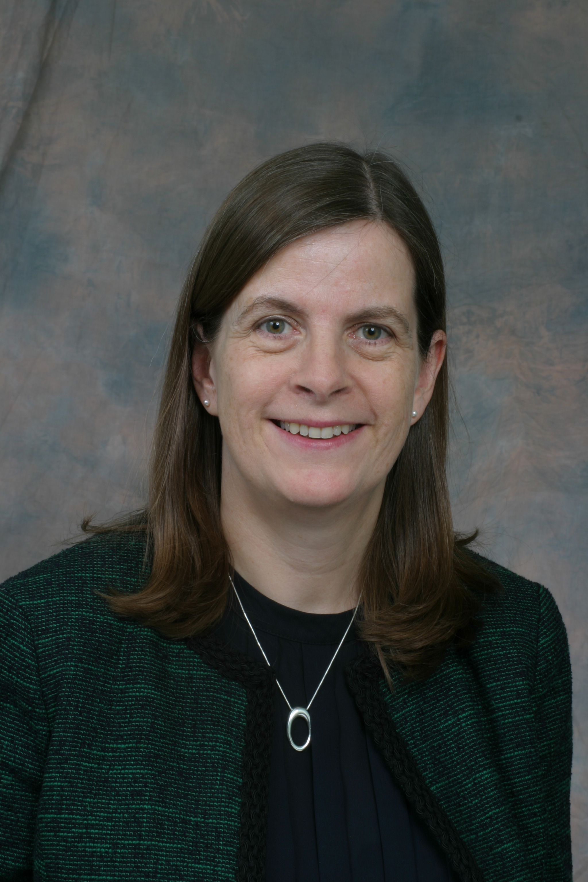 Person with long hair smiling against a textured background.