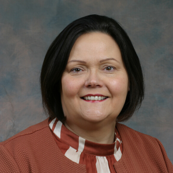 Person smiling in a professional portrait against a blue background.