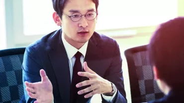 Person in a suit discussing with another individual at a meeting.