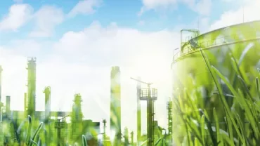 Industrial plant with green energy theme, grass in foreground.