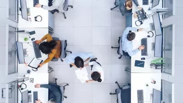 Aerial view of office workers at desks using computers and collaborating.