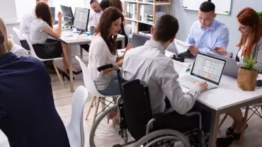 People working at desks with laptops and documents in a modern office.