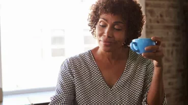 Person enjoying coffee while sitting at a desk in an office.
