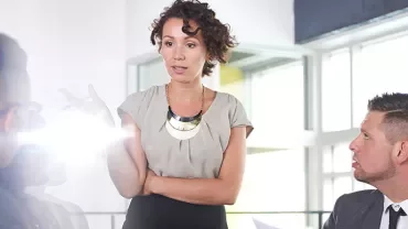 Person speaking to colleagues in a bright office.