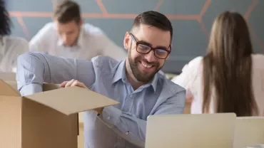 Person smiling while unpacking a box in an office