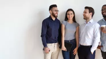 Four people standing together, smiling, with one holding a tablet.
