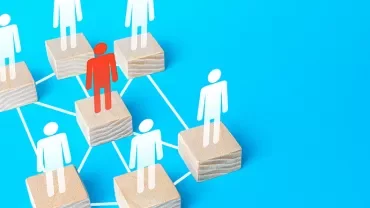 Figure on wooden block network with one highlighted in red on light blue background.