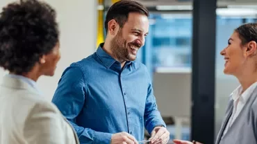 Three people having a conversation in a modern office setting.