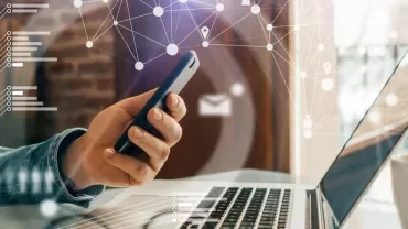 Person using smartphone and laptop with digital connections overlay.