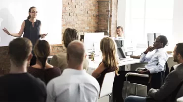Person giving a presentation to a group in a modern office setting.