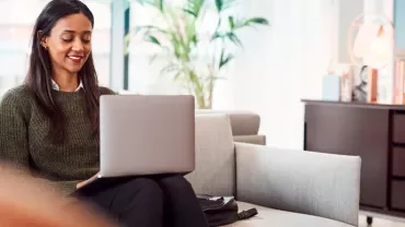 Person sitting on a couch working on a laptop in a modern office setting.