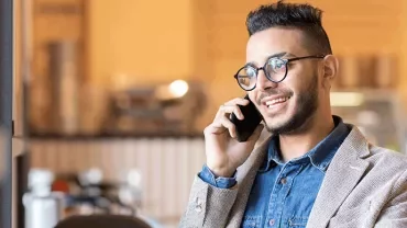 Person smiling and talking on a smartphone indoors.