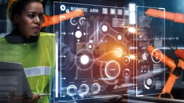 Engineer with tablet operates robotic arms via a digital interface.