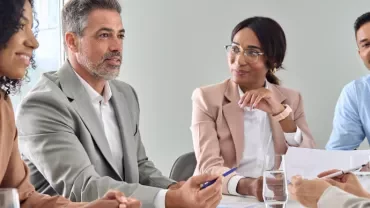 A group of people having a discussion around a table.