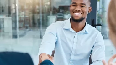 Person smiling while shaking hands in an office.