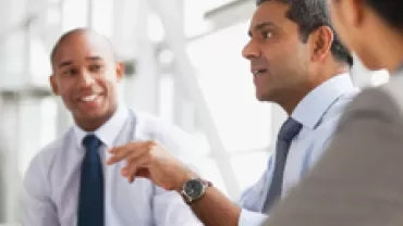 Three people in business attire having a discussion.