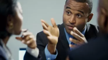 Person in a suit engaged in a discussion with colleagues.