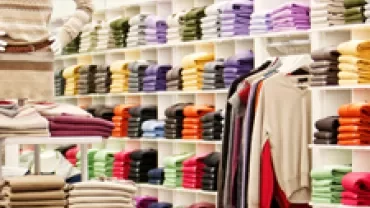 Shelves filled with neatly folded colorful sweaters in a clothing store.