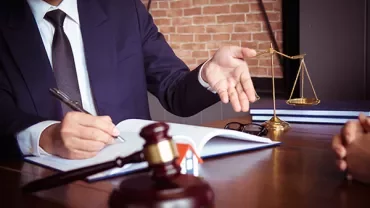 Lawyer discussing legal documents at a desk with scales and a gavel.