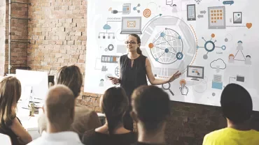 Person giving a presentation to a group with a digital network whiteboard.