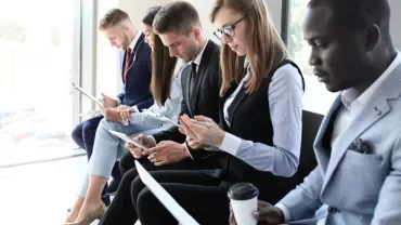 Group of people sitting with paperwork and devices in a well-lit room.